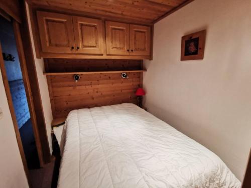 - un petit lit dans une petite chambre avec des placards en bois dans l'établissement Appartement rénové avec balcon au cœur de Méribel • Label Méribel • Non-fumeur • Casier à skis • Ascenseur - FR-1-355-31, à Méribel