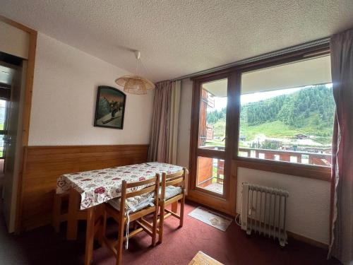 une salle à manger avec une table et une grande fenêtre dans l'établissement Appartement fonctionnel proche des pistes avec balcon et parking - FR-1-181-2173, à La Plagne Tarentaise
