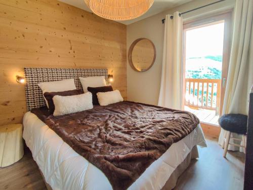 ein Schlafzimmer mit einem großen Bett mit einem großen Fenster in der Unterkunft Superbe chalet duplex 3* avec prestations hôtelières, pied de pistes, parking, wifi - FR-1-356-378 in Les Avanchers