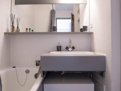La salle de bains blanche est pourvue d'un lavabo et d'une baignoire. dans l'établissement Charmant appart 23m² à Méribel Mottaret avec balcon, pied des pistes, idéal famille - FR-1-355-194, à Les Allues