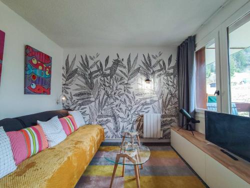 un salon avec un canapé et une télévision dans l'établissement Studio rénové au pied des pistes, balcon sud, commerces proches - FR-1-356-406, à Valmorel