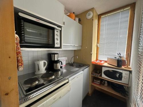une petite cuisine avec une cuisinière et un micro-ondes dans l'établissement Studio lumineux proche des pistes avec balcon - Animaux admis - FR-1-181-2368, à La Plagne Tarentaise