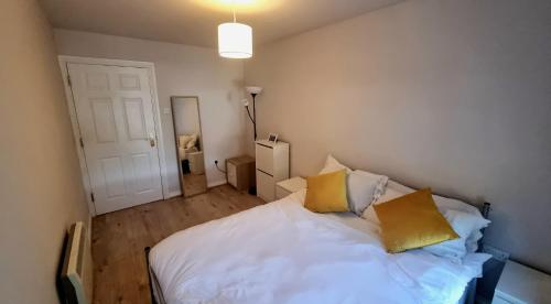 a bedroom with a white bed with two yellow pillows at Cosy 2BR Modern Apt with Free Parking in Liverpool