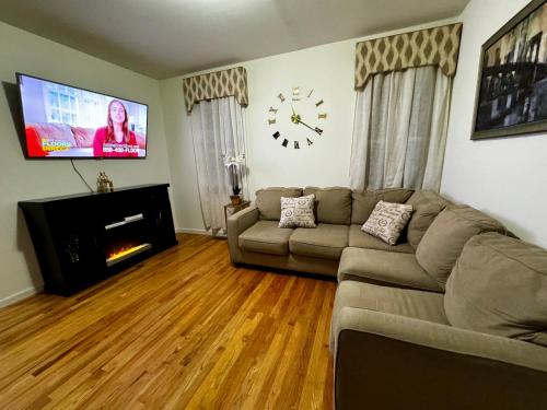a living room with a couch and a clock on the wall at Private 1st floor Apartment - Only 5 min Away from Newark Airport and 30 min to NYC in Elizabeth