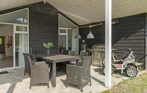 a patio with a table and a motorcycle parked next to a house at 3 Bedroom Cozy Home In Liseleje in Liseleje