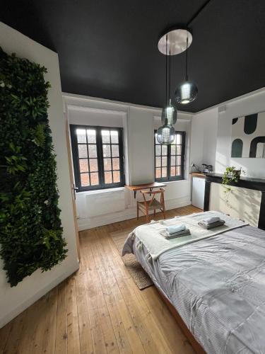 une chambre avec un lit, une table et des fenêtres dans l'établissement L'Oasis Confort, Centre-Ville, à Arras