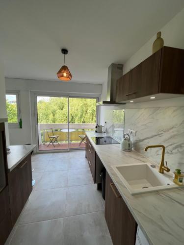 a large kitchen with a sink and a large window at Balcon sur la rivière in Périgueux