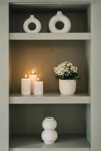 a shelf with three candles and a vase with flowers at La Demeure de la Cité by Jean Bacou in Carcassonne