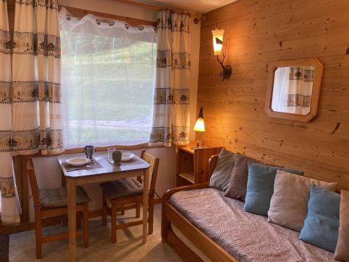 une chambre avec un lit, une table et une fenêtre dans l'établissement Studio cosy près des pistes à Valmorel, animaux admis - FR-1-356-349, à Valmorel
