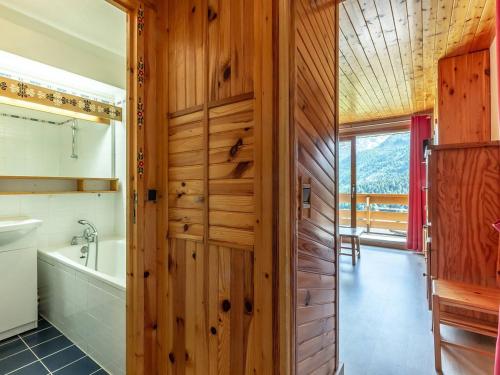 La salle de bains est pourvue d'un mur en bois et d'une baignoire. dans l'établissement Appartement skis aux pieds à Méribel avec balcon - 4 pers. - FR-1-355-122, à Méribel