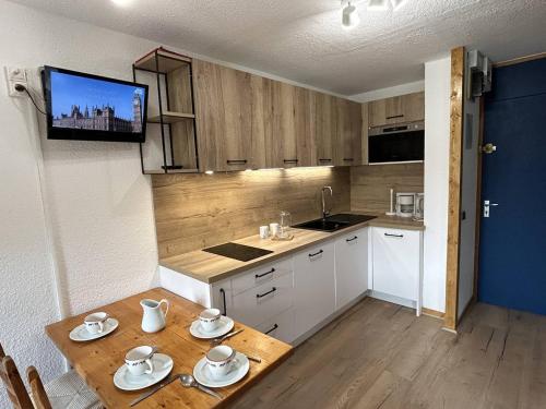Il comprend une cuisine avec une table et une télévision murale. dans l'établissement Studio divisible avec balcon, proche des pistes, animaux admis - FR-1-355-161, à Les Allues