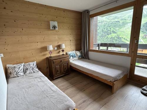 une chambre avec deux lits et une fenêtre dans l'établissement Studio divisible avec balcon, proche des pistes, animaux admis - FR-1-355-161, à Les Allues