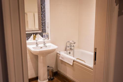 a white bathroom with a sink and a bath tub at The Red Lion Hotel in Hillingdon