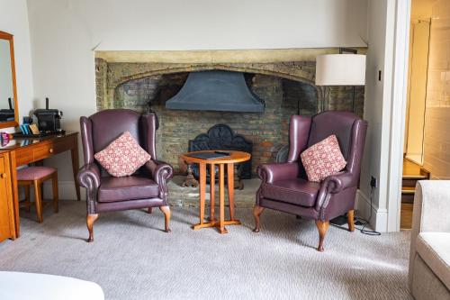 two chairs and a table in front of a fireplace at The Red Lion Hotel in Hillingdon