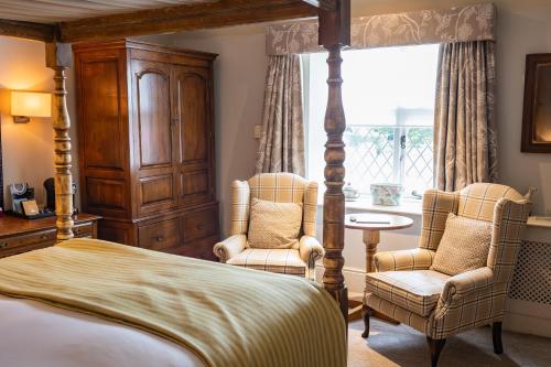 a bedroom with a bed and two chairs and a table at The Red Lion Hotel in Hillingdon