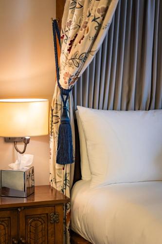 a bedroom with a bed and a table with a lamp at The Red Lion Hotel in Hillingdon