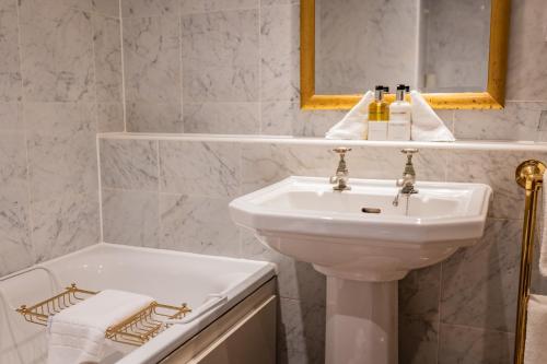 a white bathroom with a sink and a tub at The Red Lion Hotel in Hillingdon