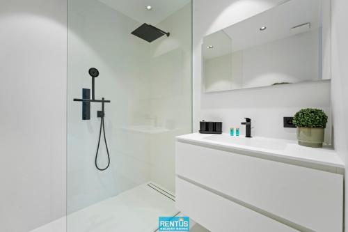 ein weißes Badezimmer mit Waschbecken und Spiegel in der Unterkunft Naast t Zand - beautifully furnished apartment with sea view in Oostduinkerke