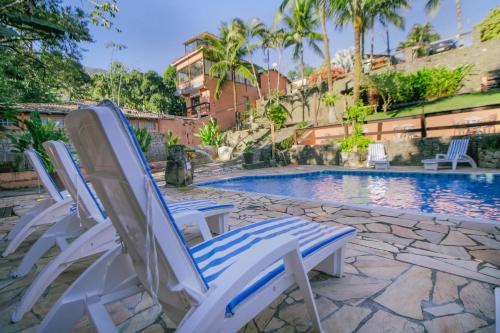 two lawn chairs sitting next to a swimming pool at VELINN Pousada Canoa Ilhabela in Ilhabela