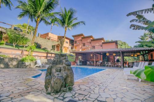 a resort pool with a statue next to a house at VELINN Pousada Canoa Ilhabela in Ilhabela