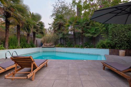 a swimming pool with two chairs and an umbrella at Hotel Director Vitacura in Santiago