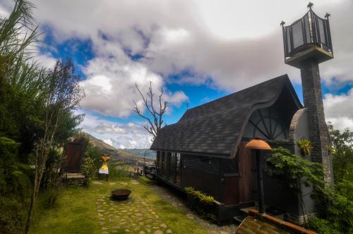 a house with a black roof and a person standing next to it at Cabin Okana in Kintamani