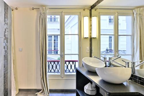 La salle de bains est pourvue de 2 lavabos et d'une grande fenêtre. dans l'établissement Grand Appartement Central Paris 150m2 - II, à Paris