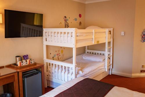 a bedroom with two bunk beds and a tv at The Red Lion Hotel in Hillingdon