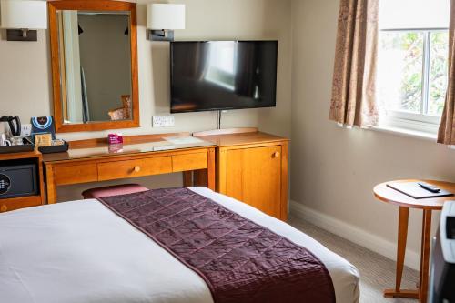 a hotel room with a bed and a television at The Red Lion Hotel in Hillingdon