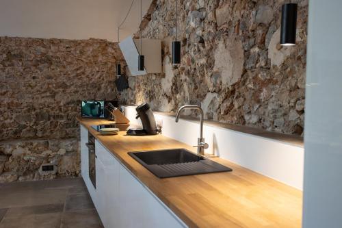 une cuisine avec un évier et un mur en pierre dans l'établissement Gites de Chateau Gasqui, à Gonfaron