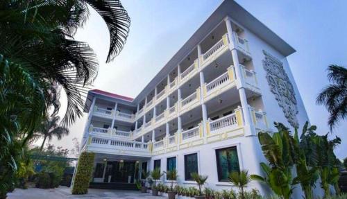 a large white building with palm trees in front of it at Hotel Royal Retreat in Sambalpur
