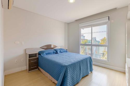 a white bedroom with a bed and a window at Apartamento em Condomínio com Piscina e Jacuzzi - Boulevard Bombinhas in Bombinhas