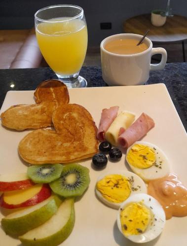 a plate of food with eggs and fruit and a cup of orange juice at Hotel Guadalupe Plaza in Pereira