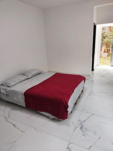 a white bedroom with a bed with a red blanket at 11Suites casa Suite #8 in Caraguatatuba