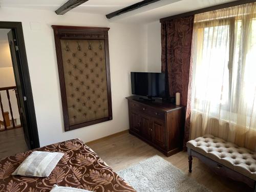 a bedroom with a bed and a tv and a window at Casa Dudu in Moieciu de Jos