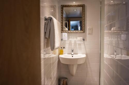 a white bathroom with a sink and a mirror at The Red Lion Hotel in Hillingdon