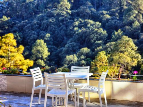 Una mesa blanca y sillas con vista a los árboles. en Solitude Inn by Epic Hospitality, en Shimla