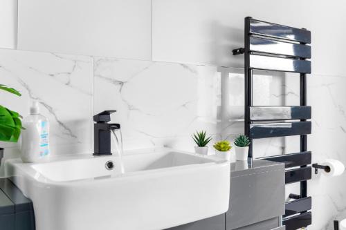 a white bathroom with a sink and a shelf at Stanion Luxurious 3 Bedroom Modern House Northamptonshire, Double, Twins, Single, Free Parking, Free Wi-Fi, Pets, Up to 8 Sleeps, 4 Smart TVs in Corby