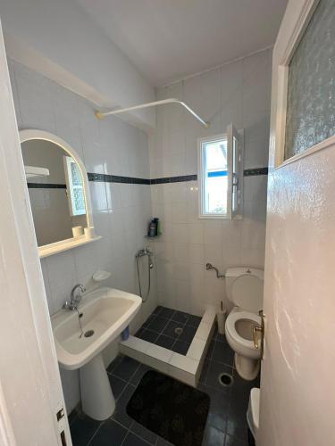 a white bathroom with a sink and a toilet at Family Apartment in Potamos Kythira in Potamós
