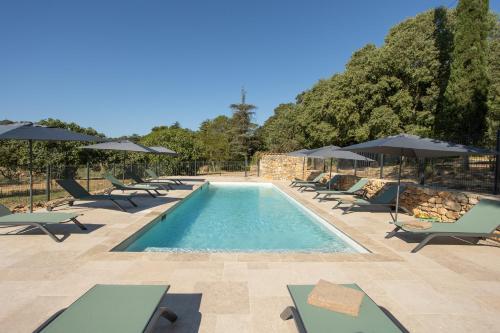 une piscine avec chaises longues et parasols dans l'établissement Gites de Chateau Gasqui, à Gonfaron