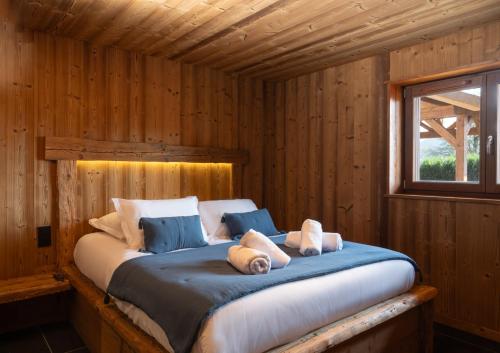 ein Bett in einer Blockhütte mit zwei Teddybären darauf in der Unterkunft Chalet 1907, pleine vue lac in Gérardmer