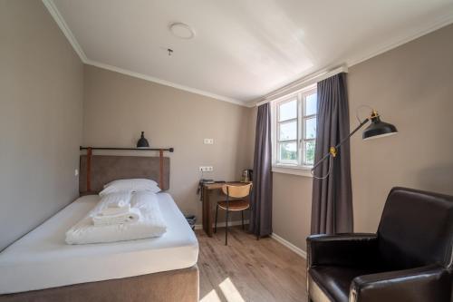a bedroom with a bed and a chair and a window at Gistihúsið - Lake Hotel Egilsstadir in Egilsstadir