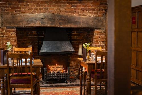 a fireplace in a room with a table and chairs at The Red Lion Hotel in Hillingdon