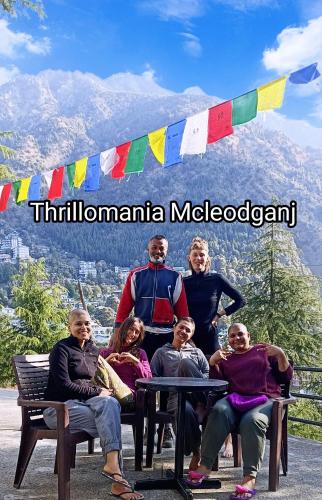 a group of people sitting at a table in front of a mountain at Thrillomania Mcleodganj in Dharamshala