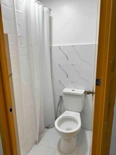 a bathroom with a toilet and a white shower curtain at Casa Olivia in Tuy