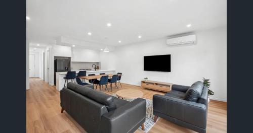 a living room with two couches and a table with chairs at "Elegant Home in Highton near City City" in Geelong