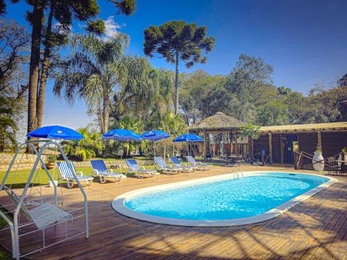 La Dolce Vita Park Hotel في ساو خوسيه دوس بينيس: مسبح مع كراسي ومظلات زرقاء