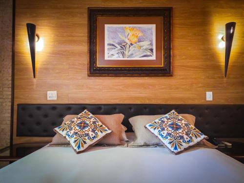 a bedroom with a bed with pillows and a painting at La Dolce Vita Park Hotel - Próximo a Curitiba in São José dos Pinhais