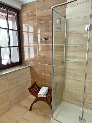 a glass shower in a bathroom with a chair at Agroturystyka Kociołek in Kociołki