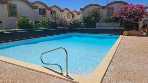 une grande piscine avec une main courante en face d'un bâtiment dans l'établissement Studio avec accès direct sur le port de Gruissan, à Gruissan